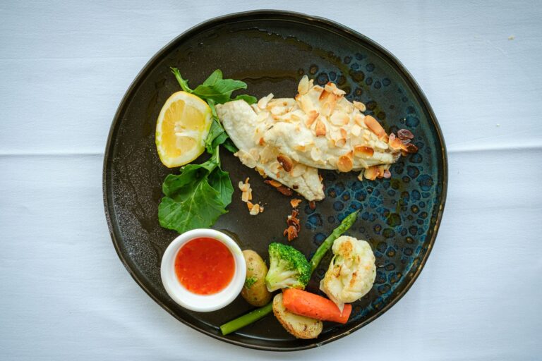 Baked cod with golden herb crust and lemon slices on dark baking dish
