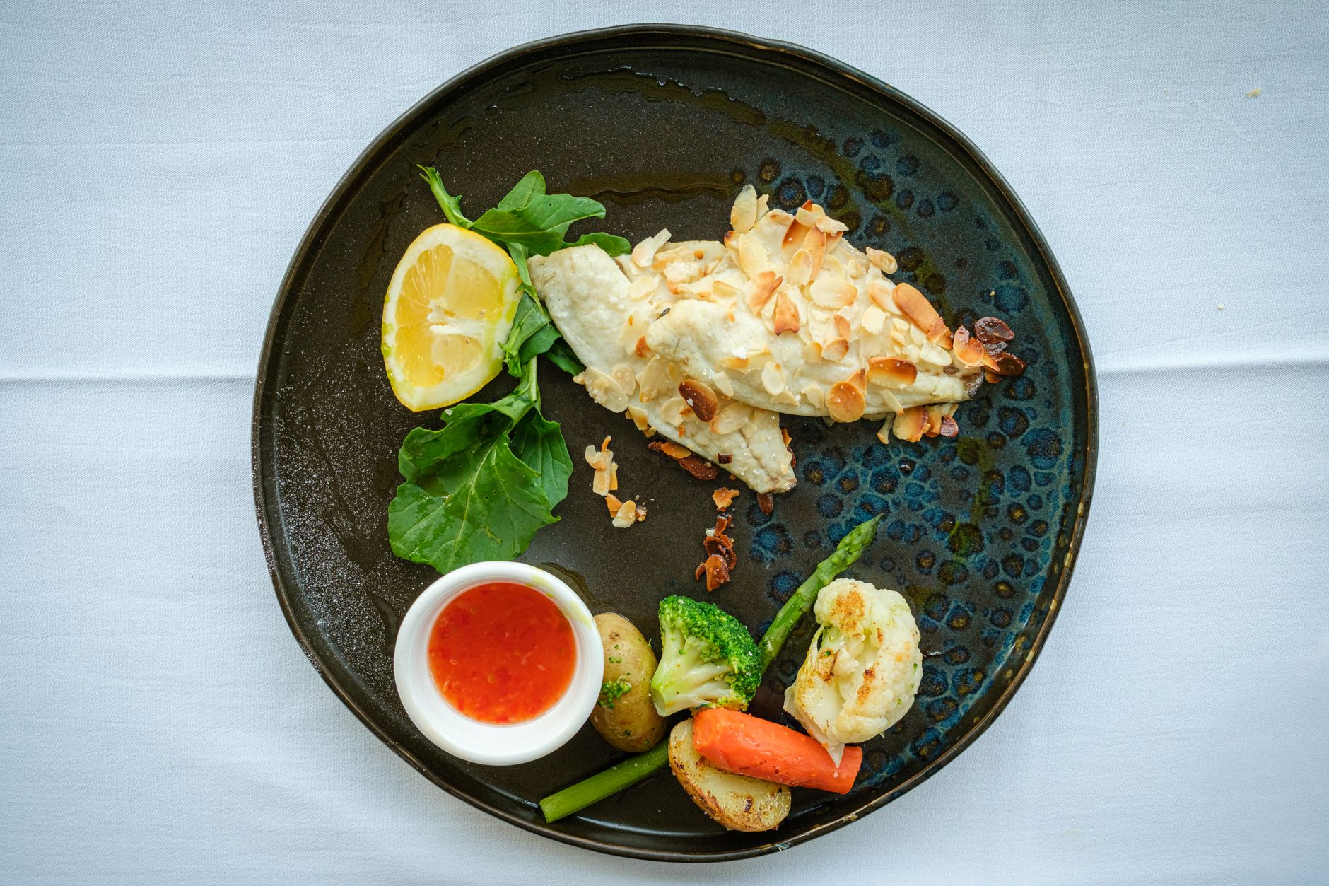Baked cod with golden herb crust and lemon slices on dark baking dish