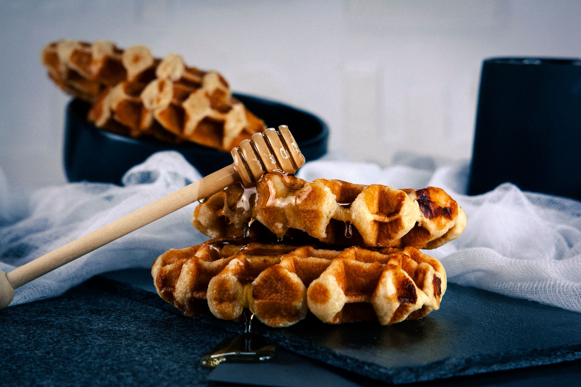 Golden banana protein waffles with sliced banana and honey drizzle on dark plate
