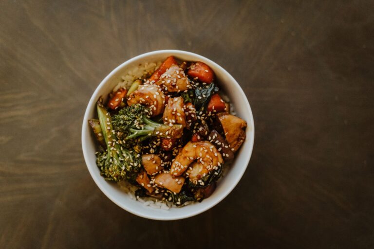 Beef and broccoli stir-fry with glossy sauce over white rice in dark bowl