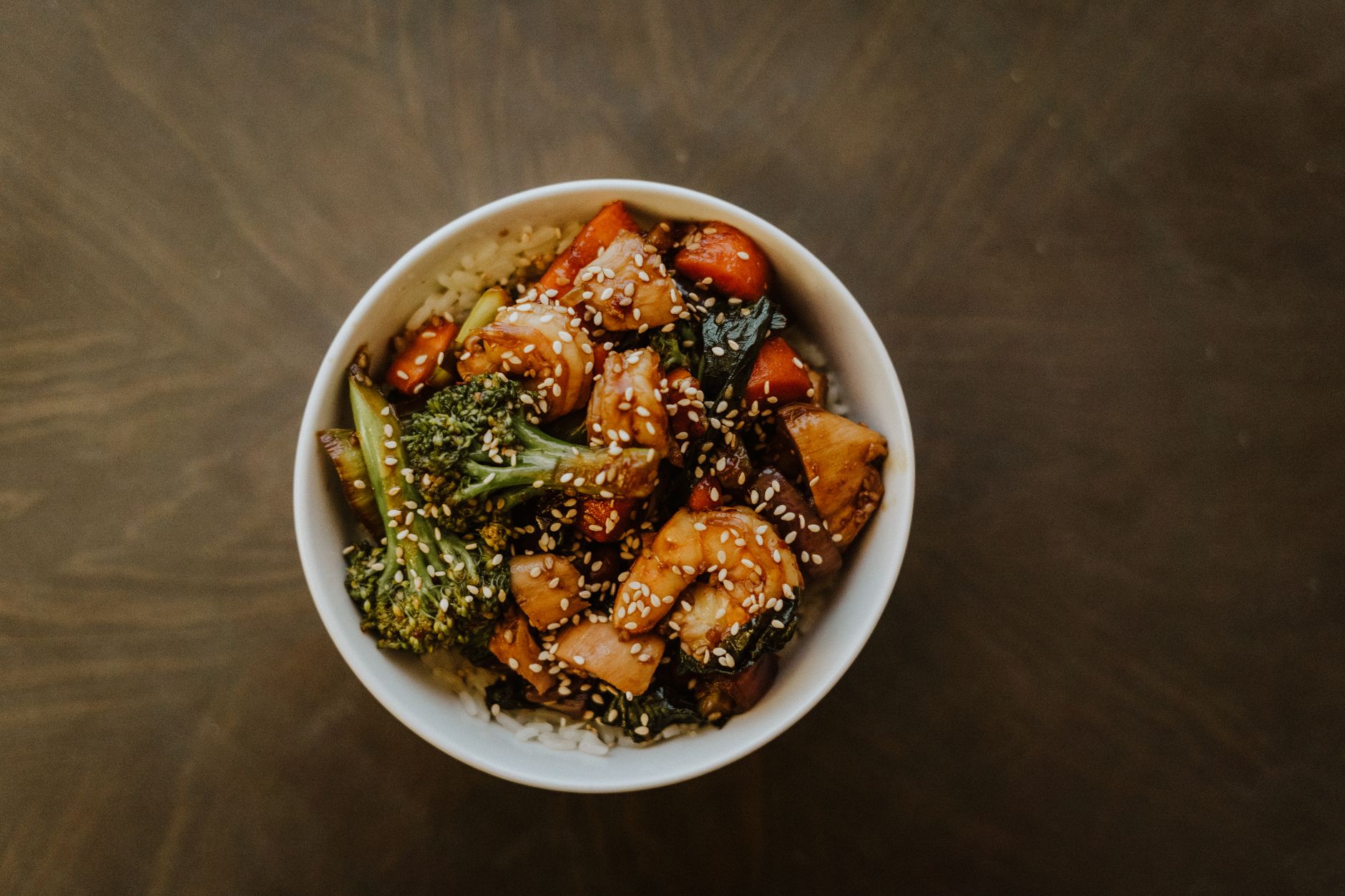 Beef and broccoli stir-fry with glossy sauce over white rice in dark bowl