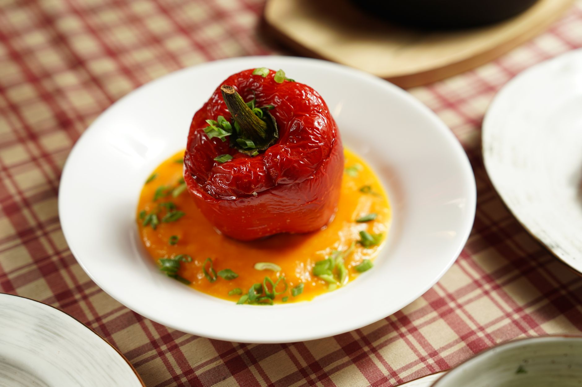 Buffalo chicken stuffed peppers with cream cheese topping in dark baking dish