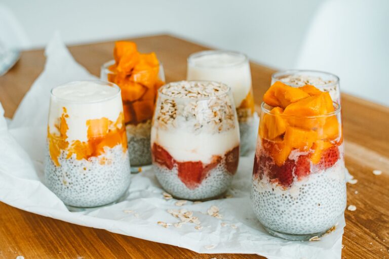 Chia seed protein pudding in glass jar with mango and coconut flakes on dark background