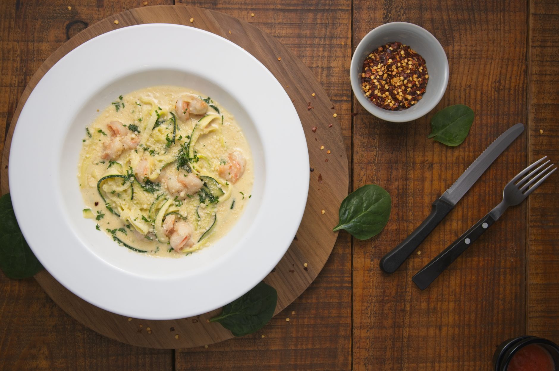 Garlic butter shrimp on zucchini noodles with lemon and parsley in dark bowl