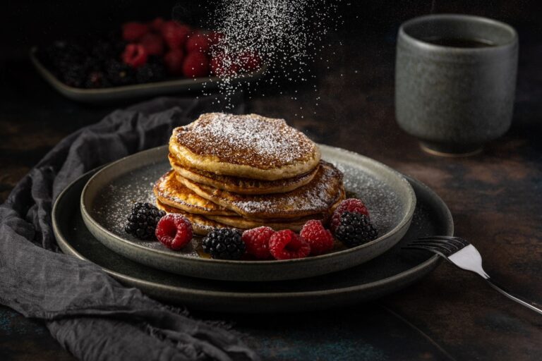 Stack of fluffy Greek yogurt protein pancakes with maple syrup on dark background