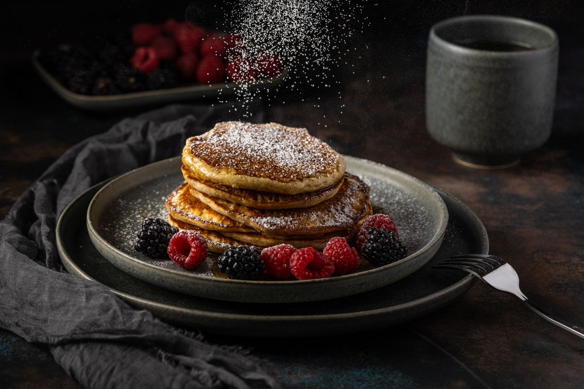Stack of fluffy Greek yogurt protein pancakes with maple syrup on dark background