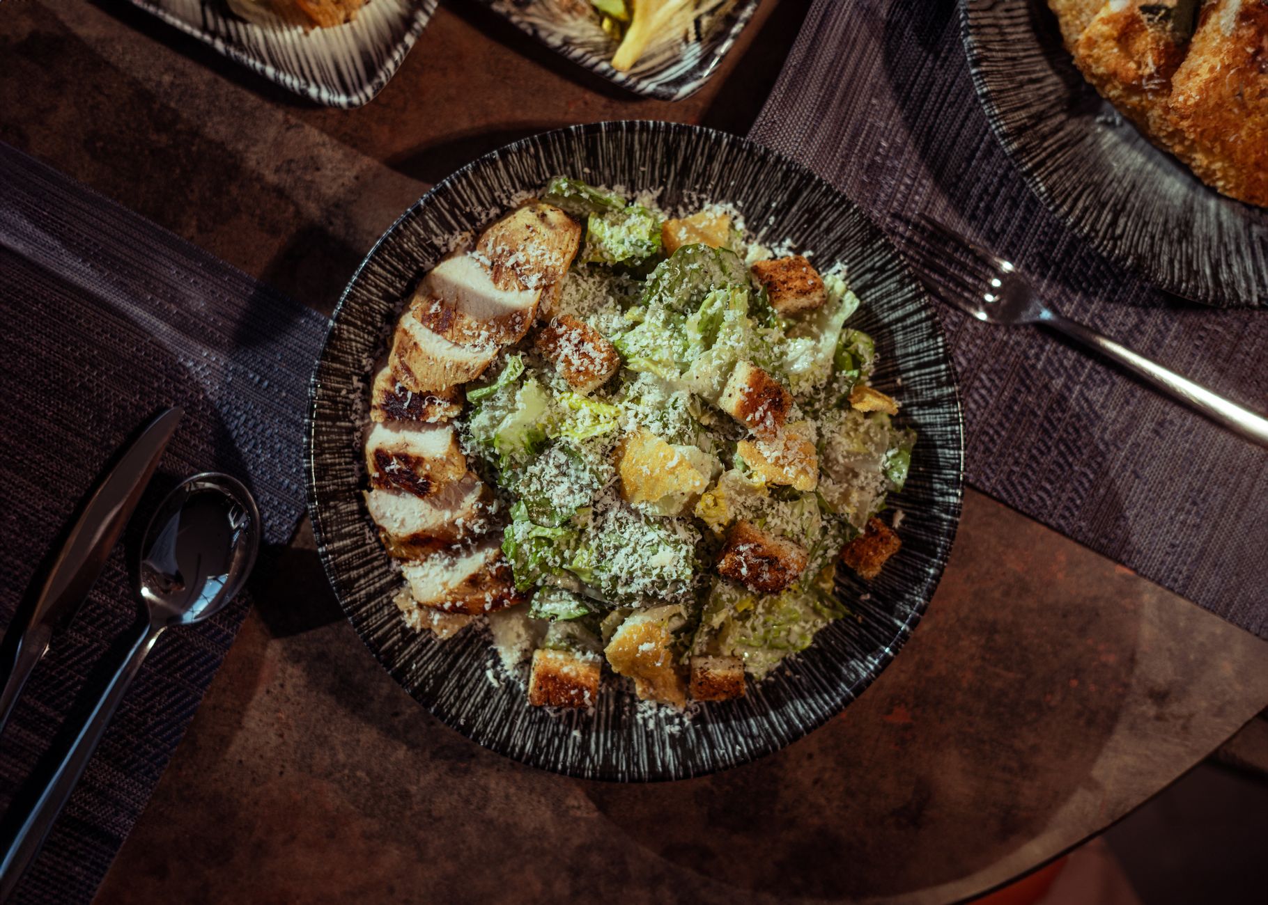High-protein chicken Caesar salad with grilled chicken and parmesan on dark plate