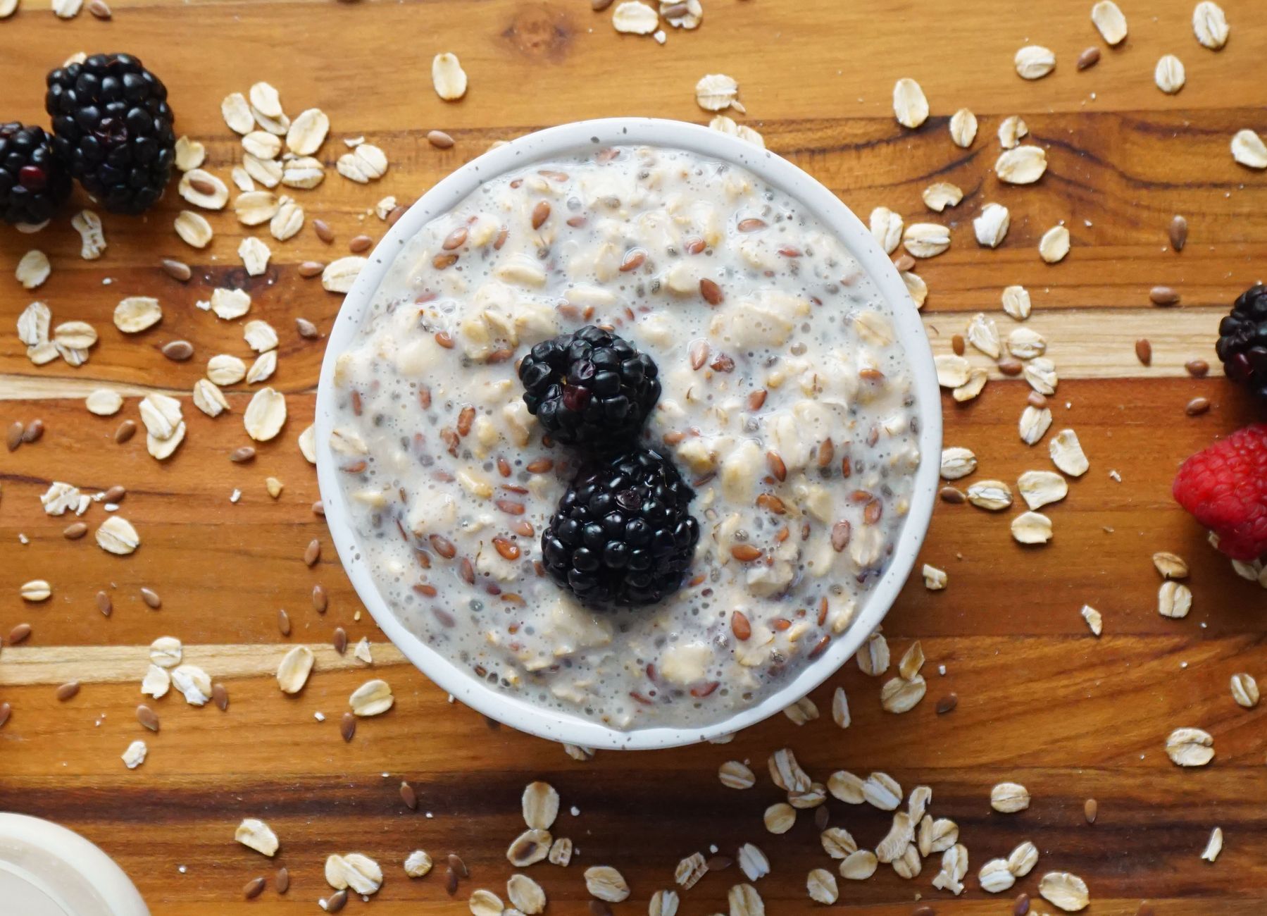 High-protein overnight oats in glass jar with berries and chia seeds on dark background
