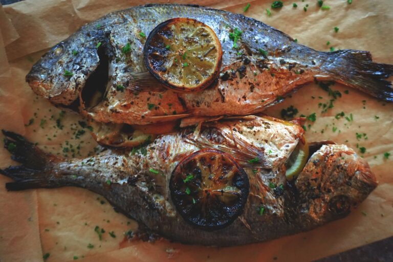 Lemon herb baked tilapia with fresh herbs and lemon slices on dark baking dish