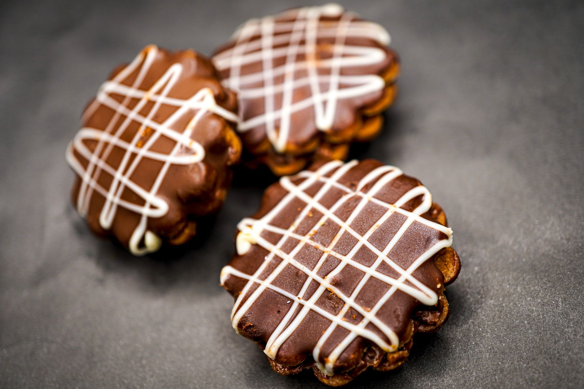 Protein rice crispy treats cut into squares with chocolate drizzle on dark parchment