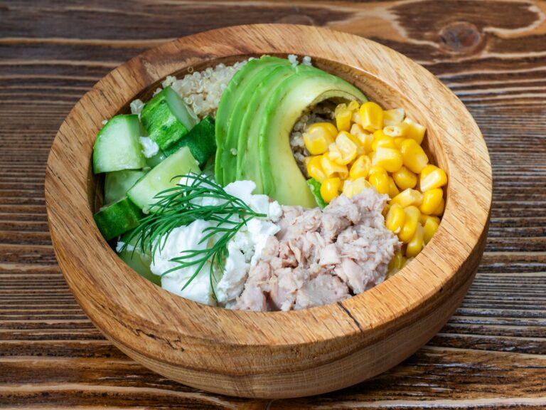 Quinoa black bean power bowl with corn, avocado and lime in dark ceramic bowl