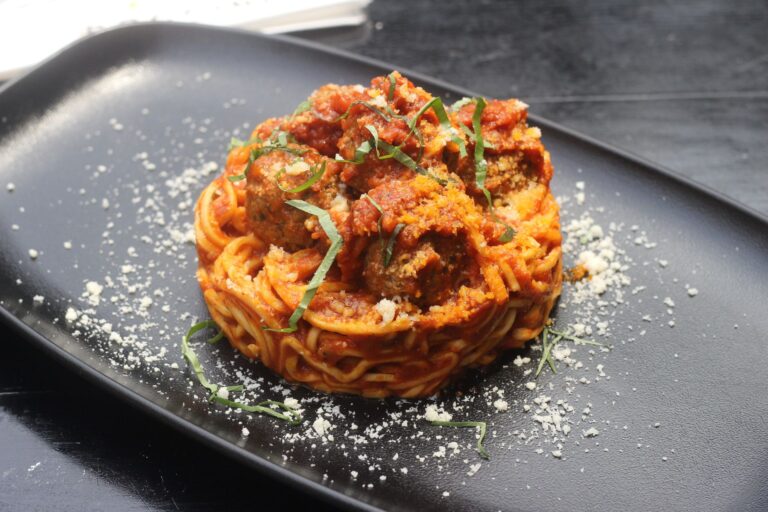Spicy turkey meatballs in tomato sauce with fresh basil on dark plate