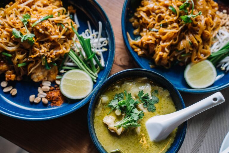 Thai peanut chicken noodles with crushed peanuts and cilantro in dark ceramic bowl