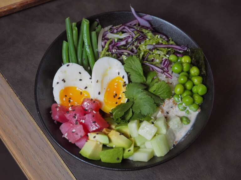 Tuna avocado rice bowl with edamame and sesame seeds in dark ceramic bowl