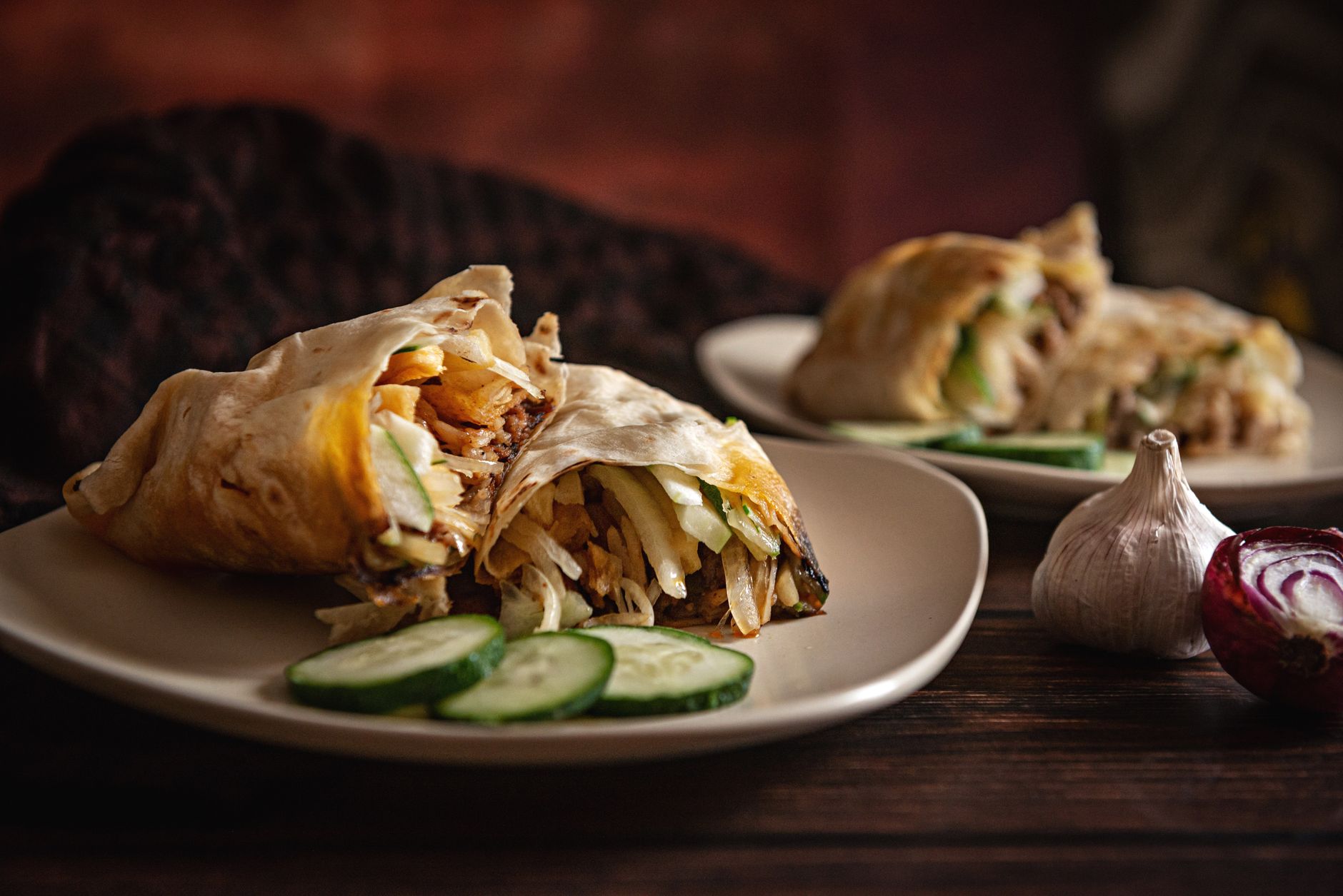Turkey avocado club wrap cut in half showing filling on dark wood board