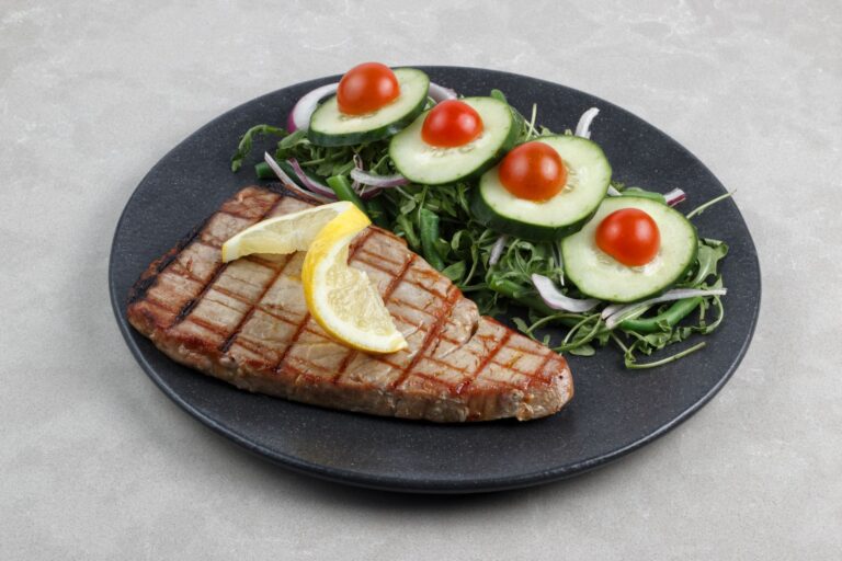 White bean tuna salad with red onion and parsley on dark plate